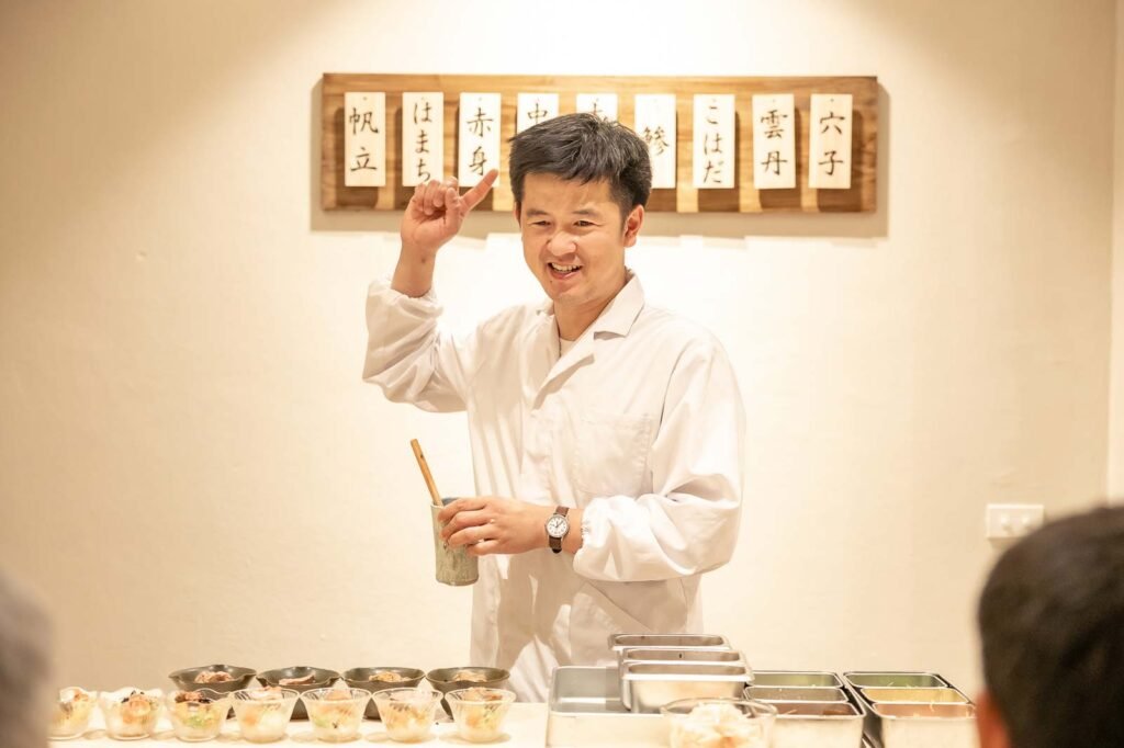 เชฟกำลังพูดคุยกับลูกค้าด้วยรอยยิ้มในบรรยากาศอบอุ่น เป็นกันเอง ภายในร้านโอมากาเสะเชียงราย